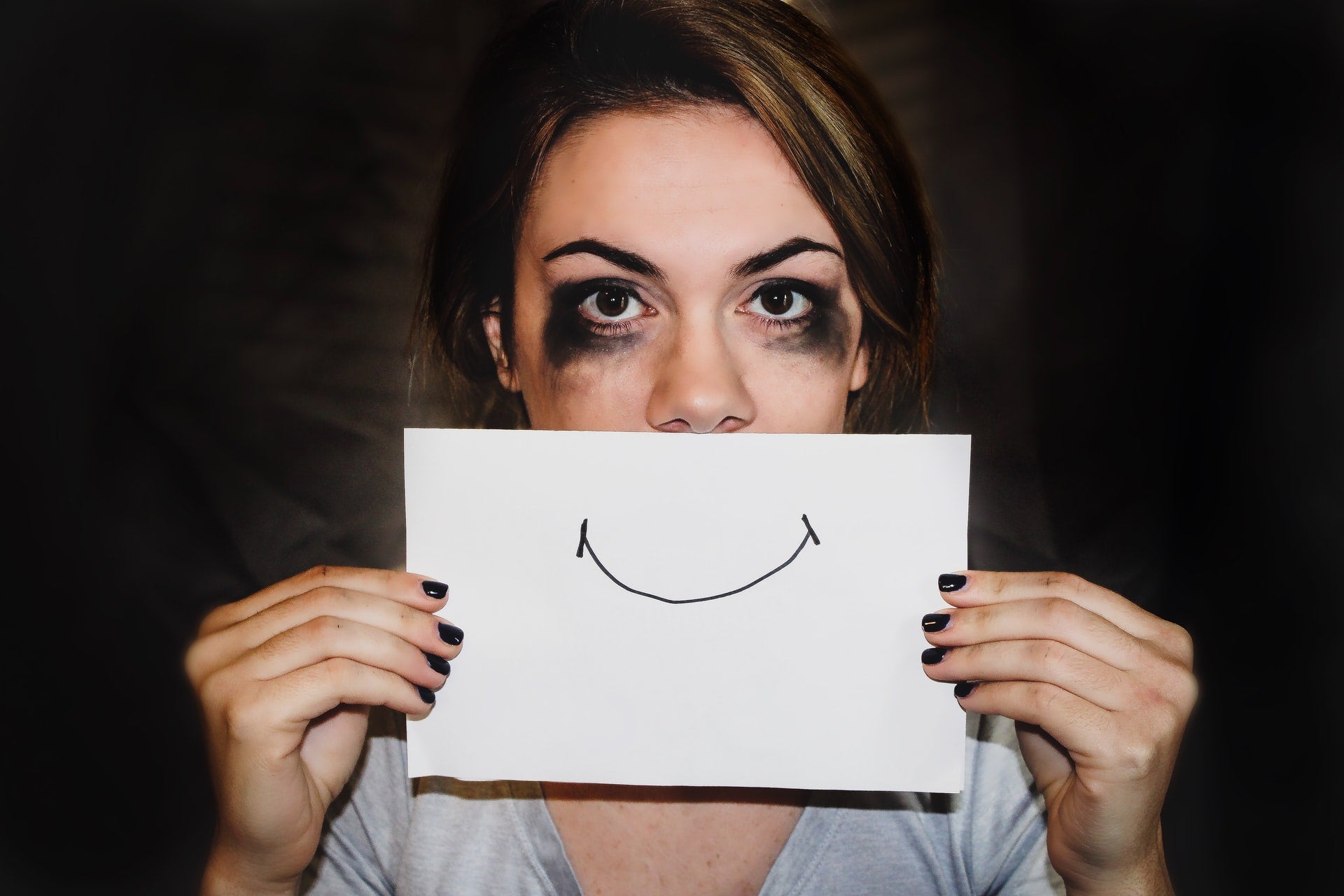 femme qui pleure avec un smiley dessiné sur la bouche